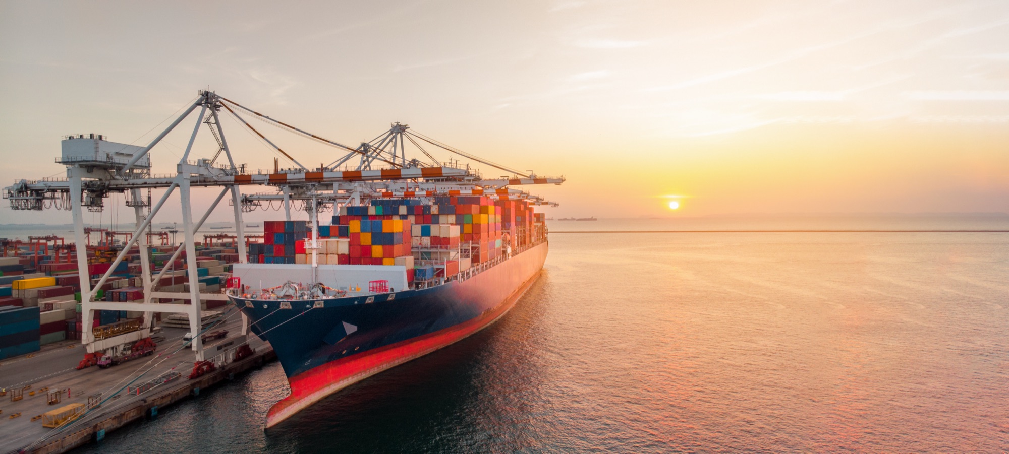 Terminal crane loading cargo at a port at sunset